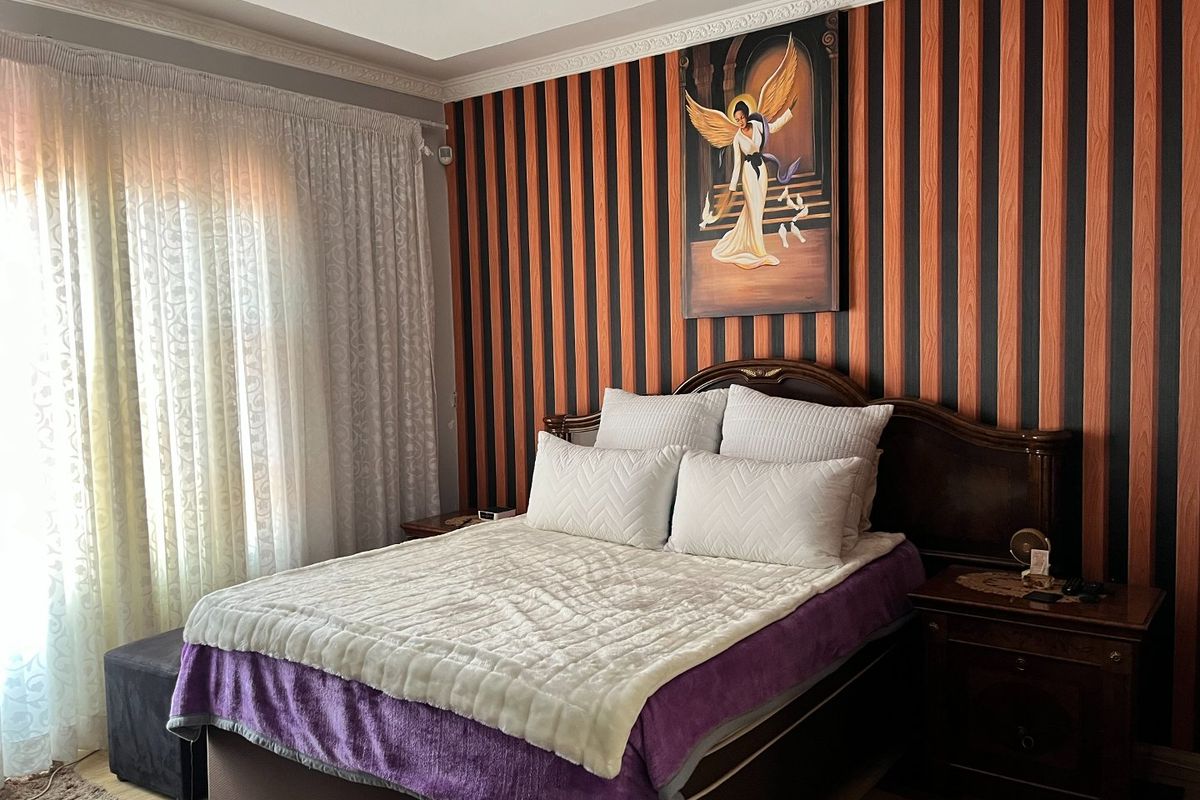 A bedroom featuring decorative crown molding and a large window with curtain tracks, providing a functional space for rest.