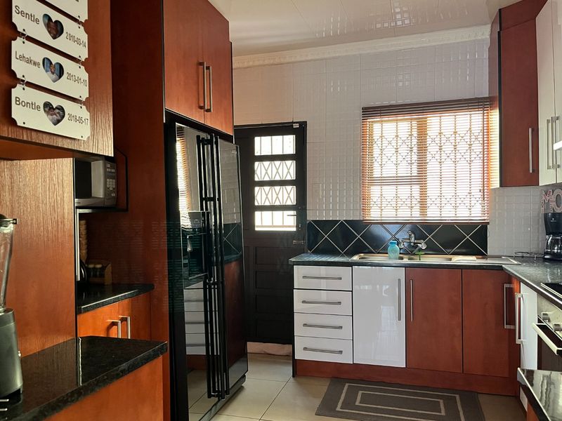 A functional kitchen featuring wood-finish cabinetry, granite countertops, tiled backsplash, and a secure exterior door with security gate.