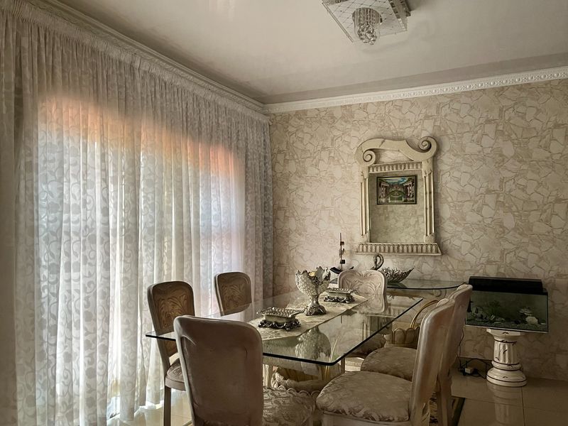 A formal dining room featuring textured wallpaper, decorative crown molding, and large sliding glass doors that provide ample natural light.