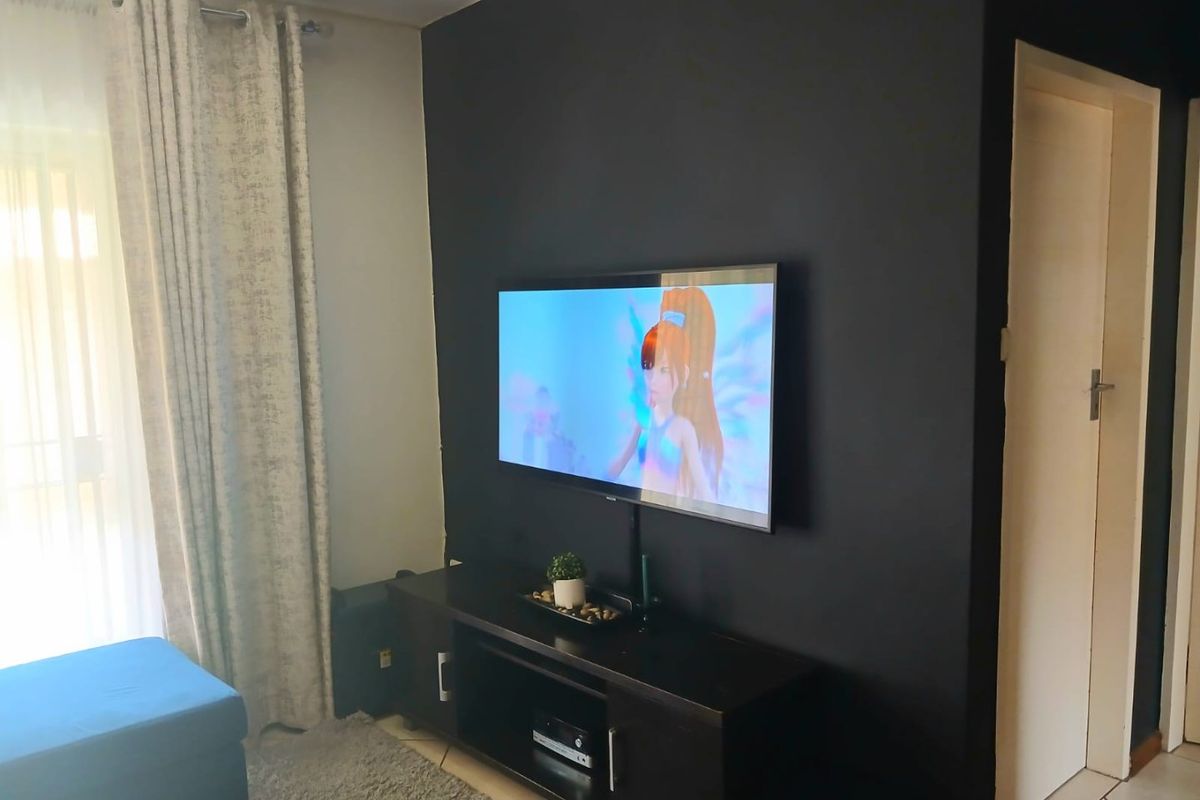 A living room area featuring a dark accent wall with a wall-mounted television and tiled flooring.