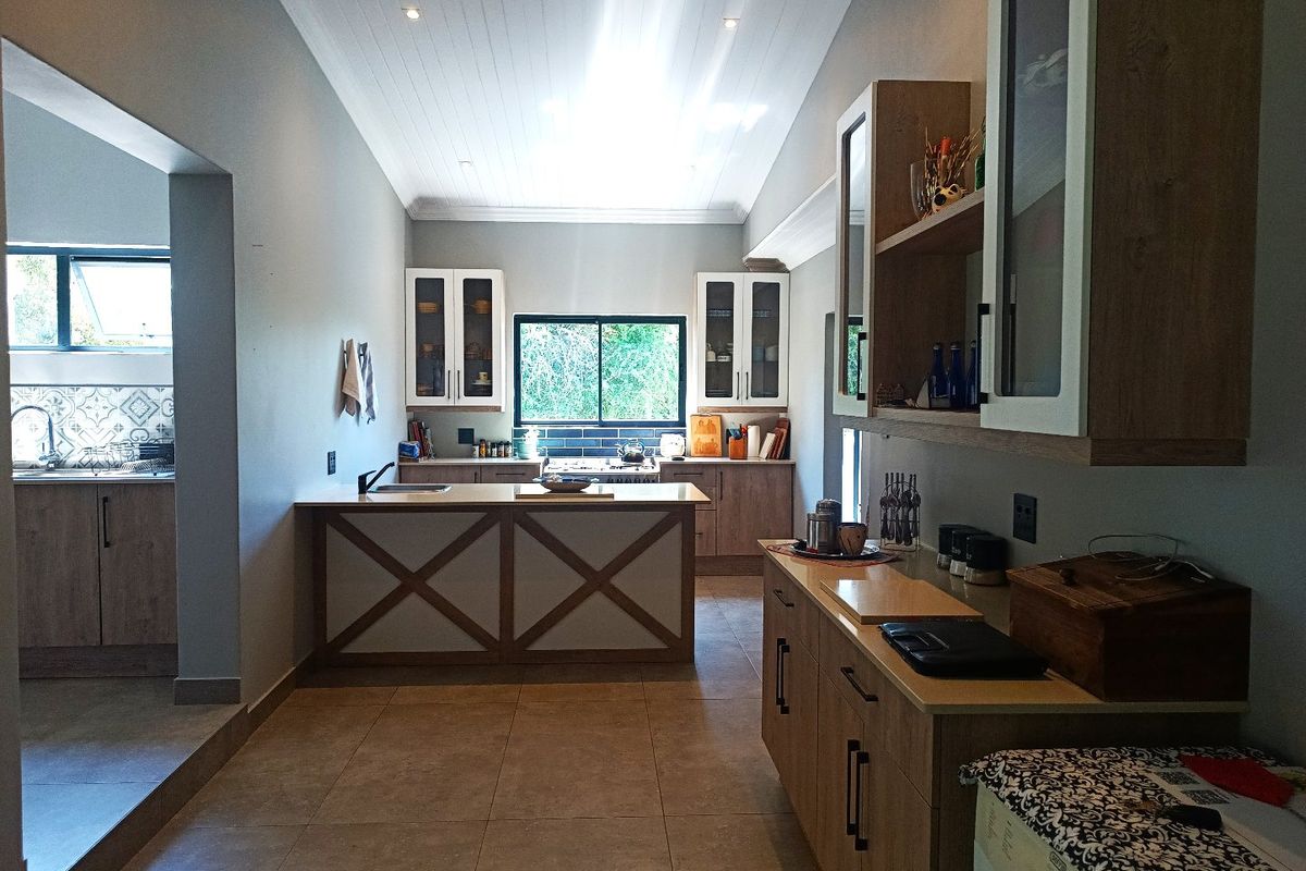 Modern farmhouse kitchen featuring a central island, extensive built-in cabinetry, tiled flooring, and a vaulted tongue and groove ceiling with recessed lighting.