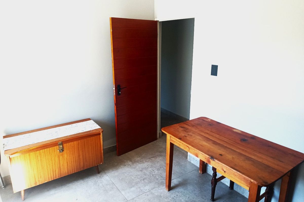 A simple bedroom interior featuring tiled flooring and a timber door, providing a neutral space ready for personalization.