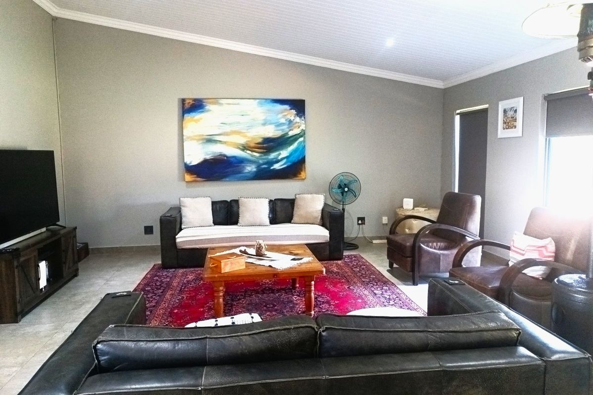 A spacious living room featuring tiled flooring, recessed downlighting, and a coved ceiling, providing a comfortable and well-maintained area for relaxation.