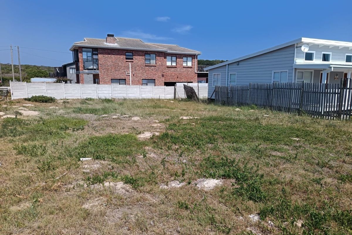 A vacant residential plot featuring a mix of precast concrete and timber boundary fencing, situated in a developed neighborhood.