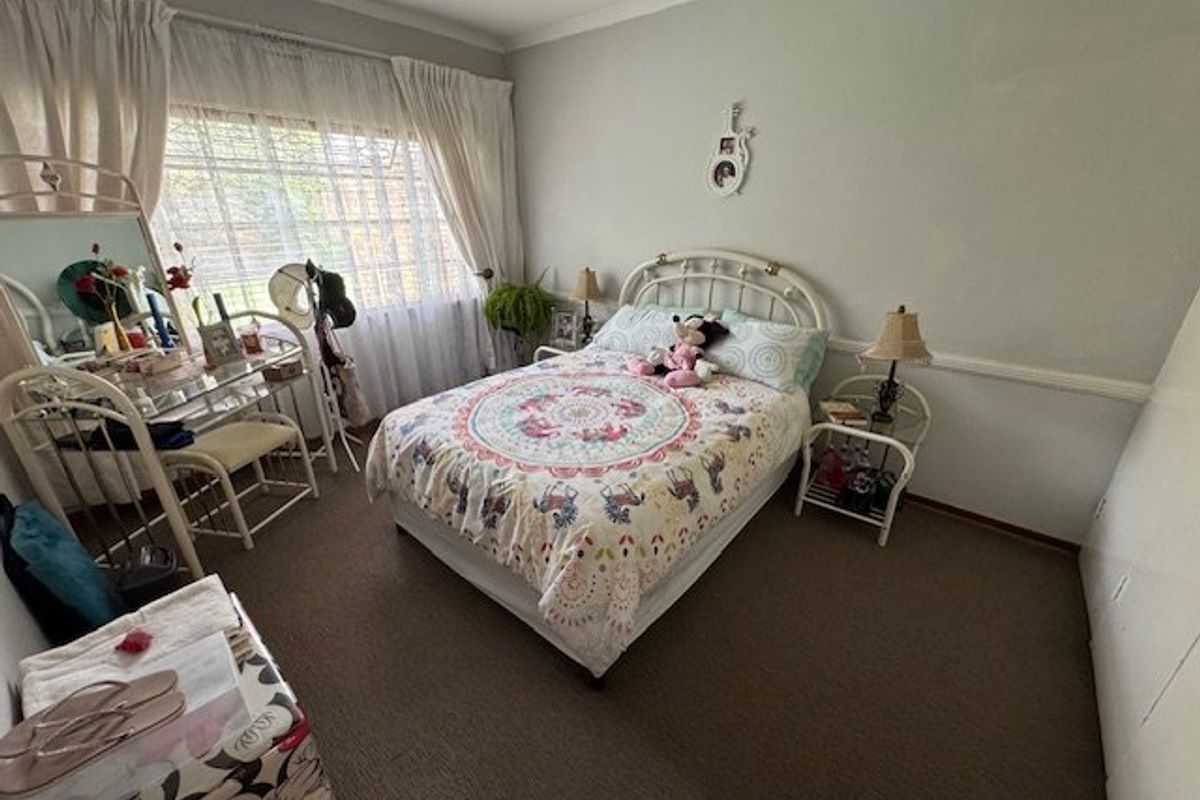 A standard bedroom featuring carpeted flooring, a ceiling fan, and decorative chair rail molding.