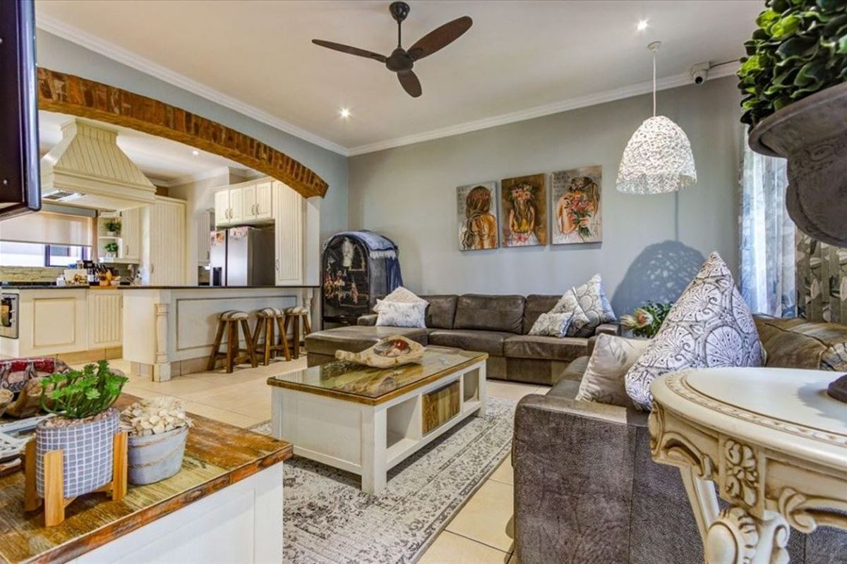 Spacious open-plan living area featuring an exposed brick archway connecting to a well-appointed kitchen with island seating and modern lighting fixtures.