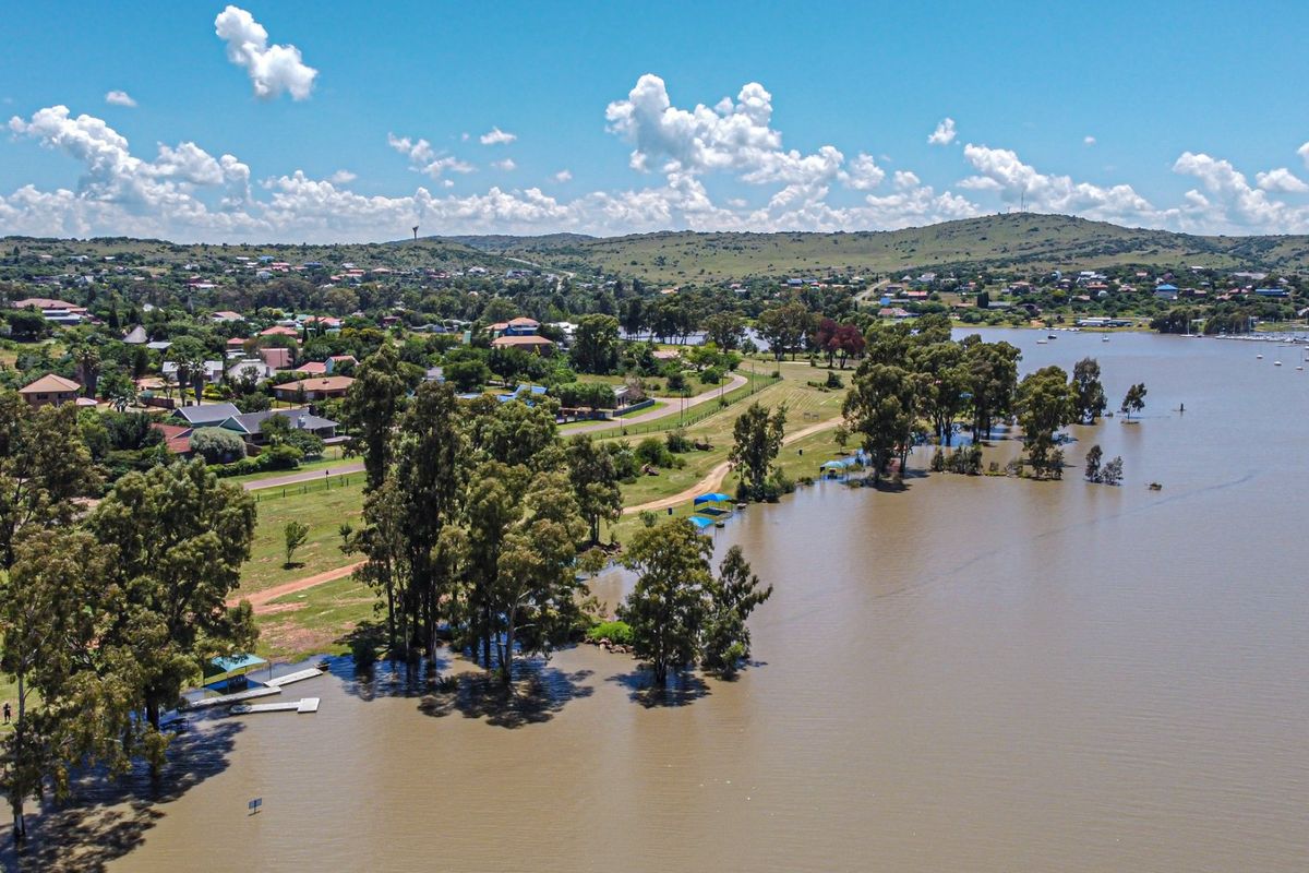 An aerial view of the surrounding landscape, featuring a large lake, parkland, and a small jetty.