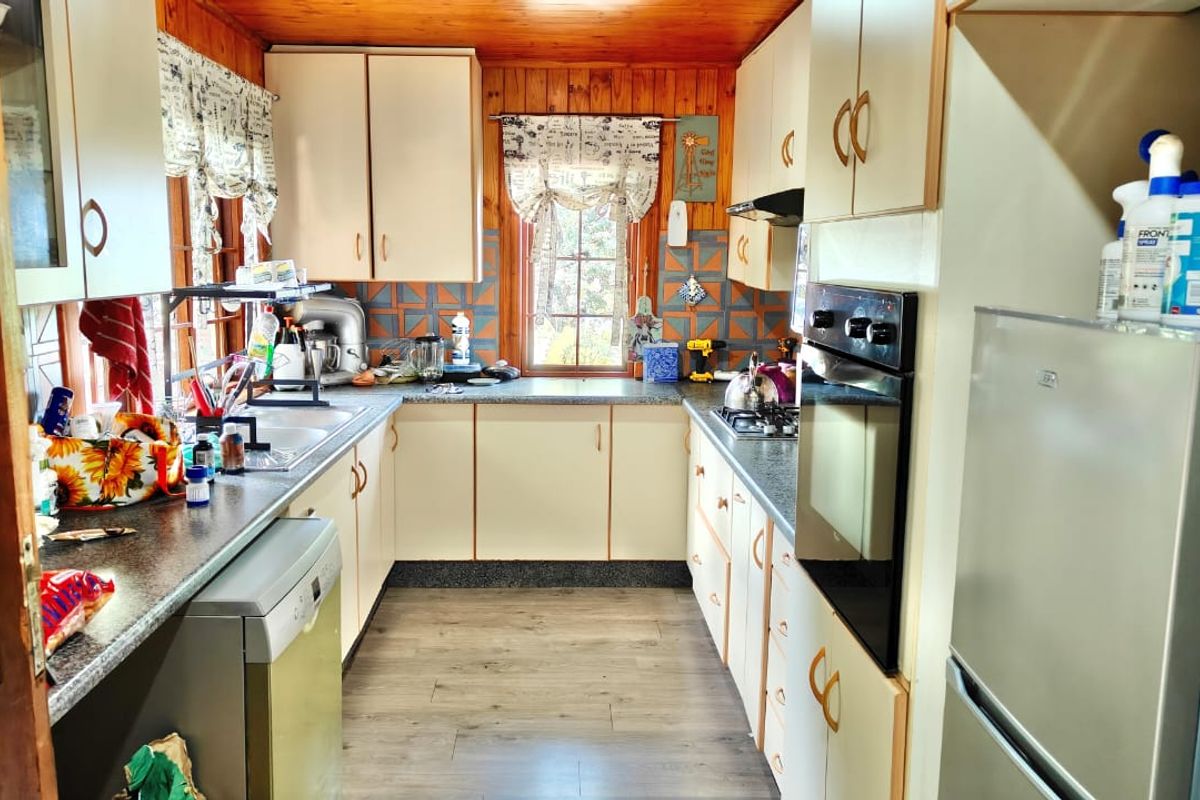 A functional U-shaped kitchen featuring built-in cabinetry, a tiled backsplash, integrated oven and hob, and timber ceiling finishes.