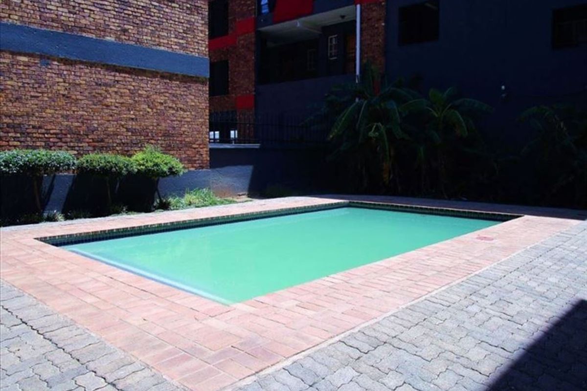 A communal swimming pool area featuring brick paving and surrounding brick building facades.