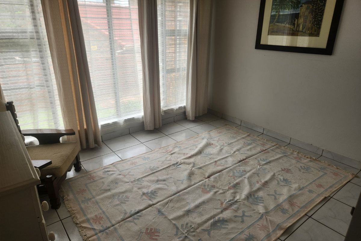 A bright living area featuring large windows that provide ample natural light and neutral tiled flooring throughout the space.