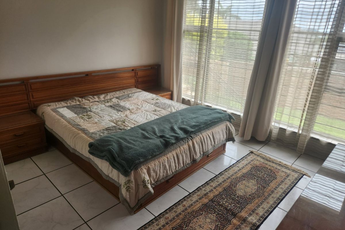A bedroom featuring tiled flooring and a large window with natural light, providing a neutral base for potential interior updates.
