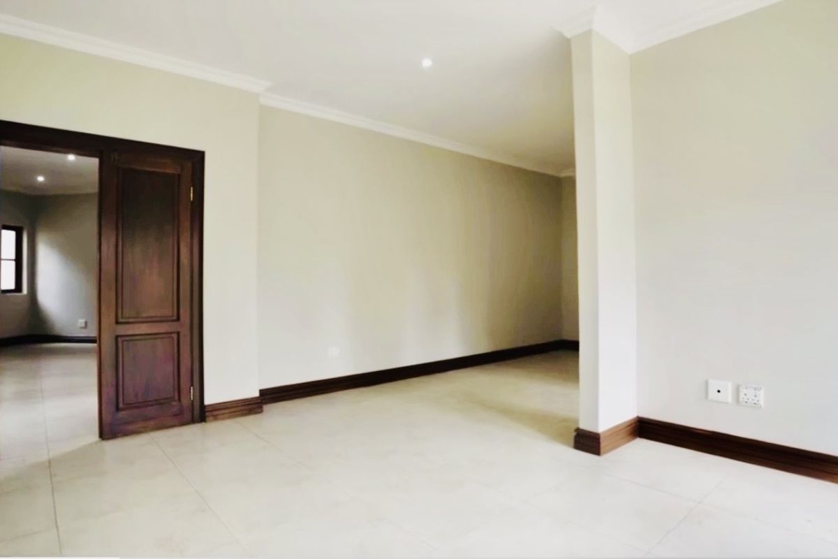 A bright, spacious, and empty living area featuring neutral tiled flooring, timber door frames, and clean finishes throughout.
