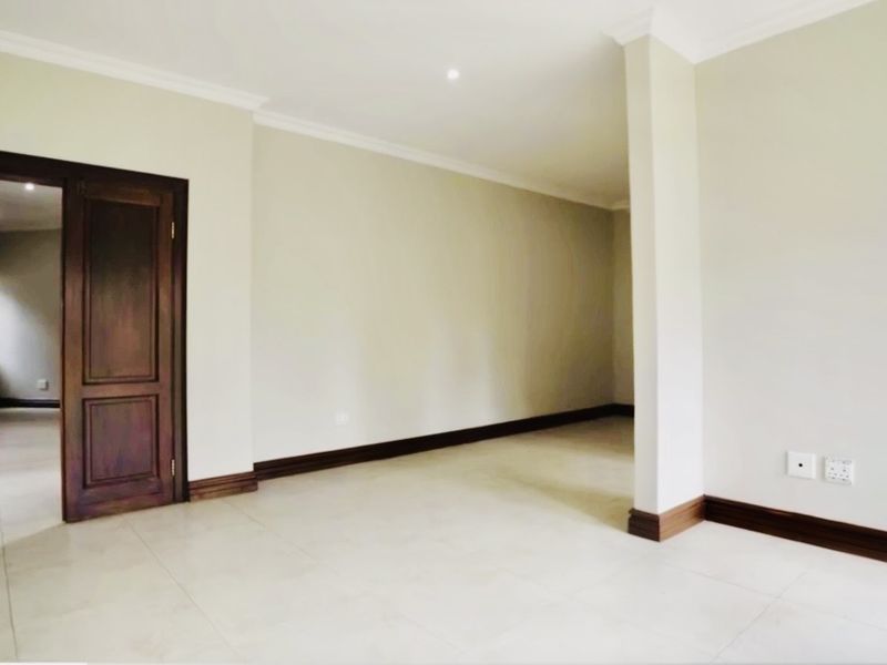 A bright, spacious, and empty living area featuring neutral tiled flooring, timber door frames, and clean finishes throughout.