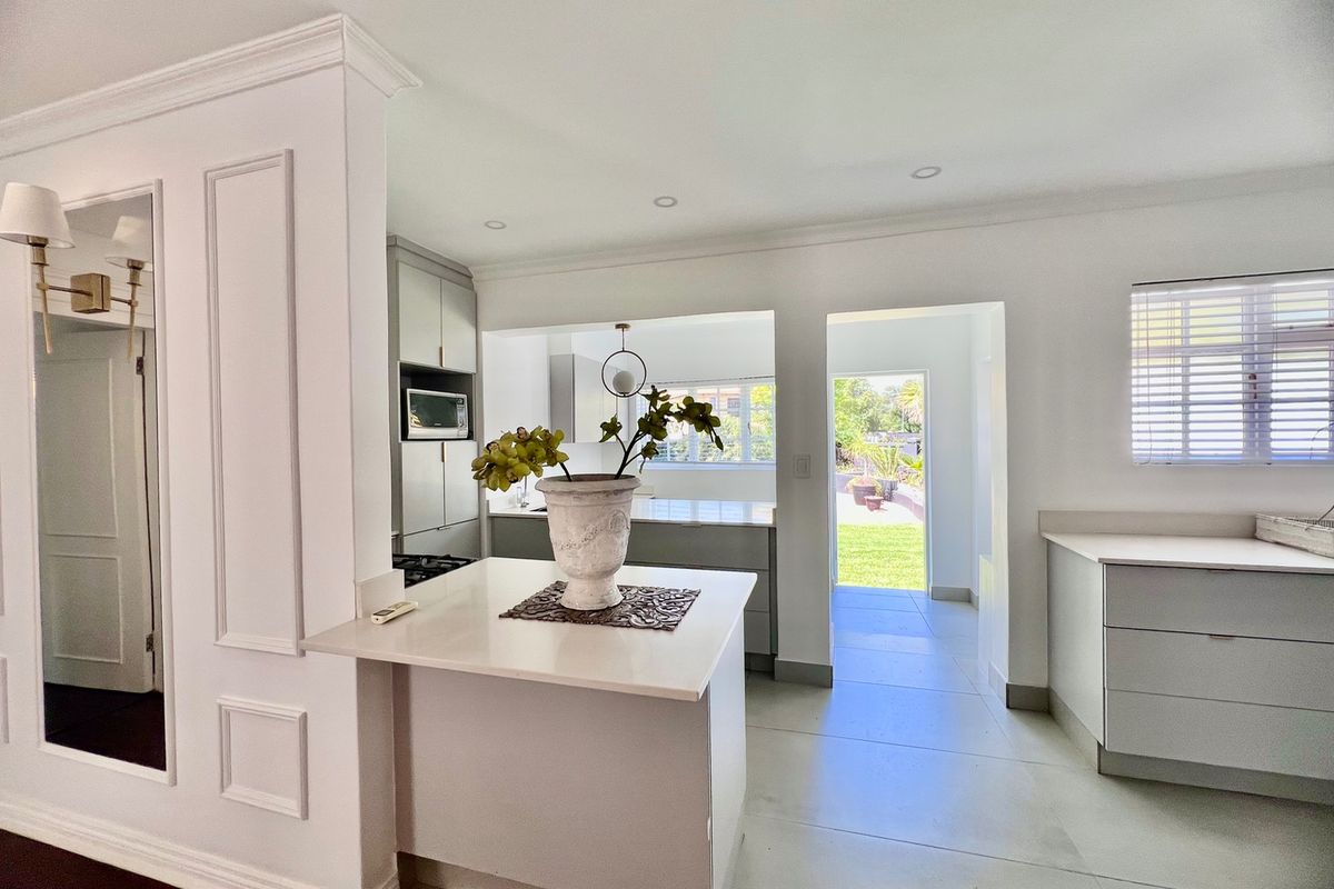Modern kitchen featuring sleek built-in cabinetry, stone countertops, recessed lighting, and direct access to the rear garden area.