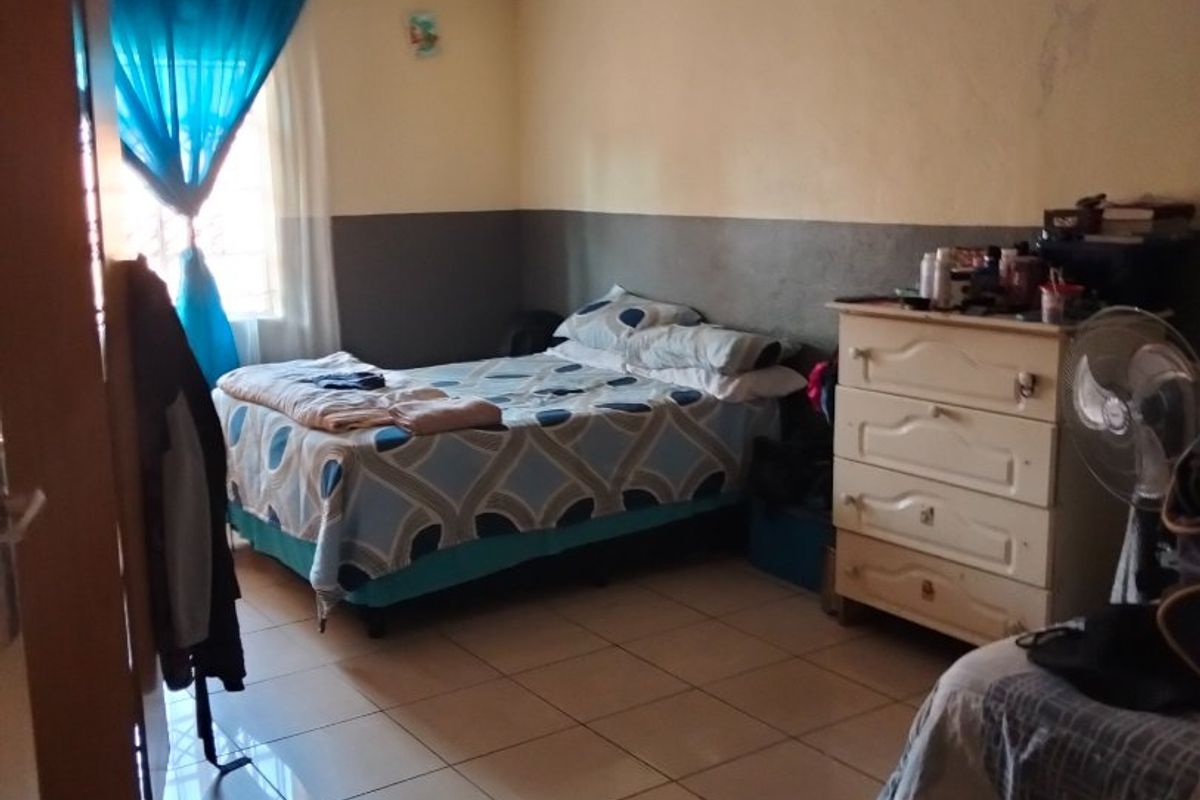 A bedroom featuring tiled flooring and a built-in cupboard, requiring minor cosmetic updates to the wall finishes.