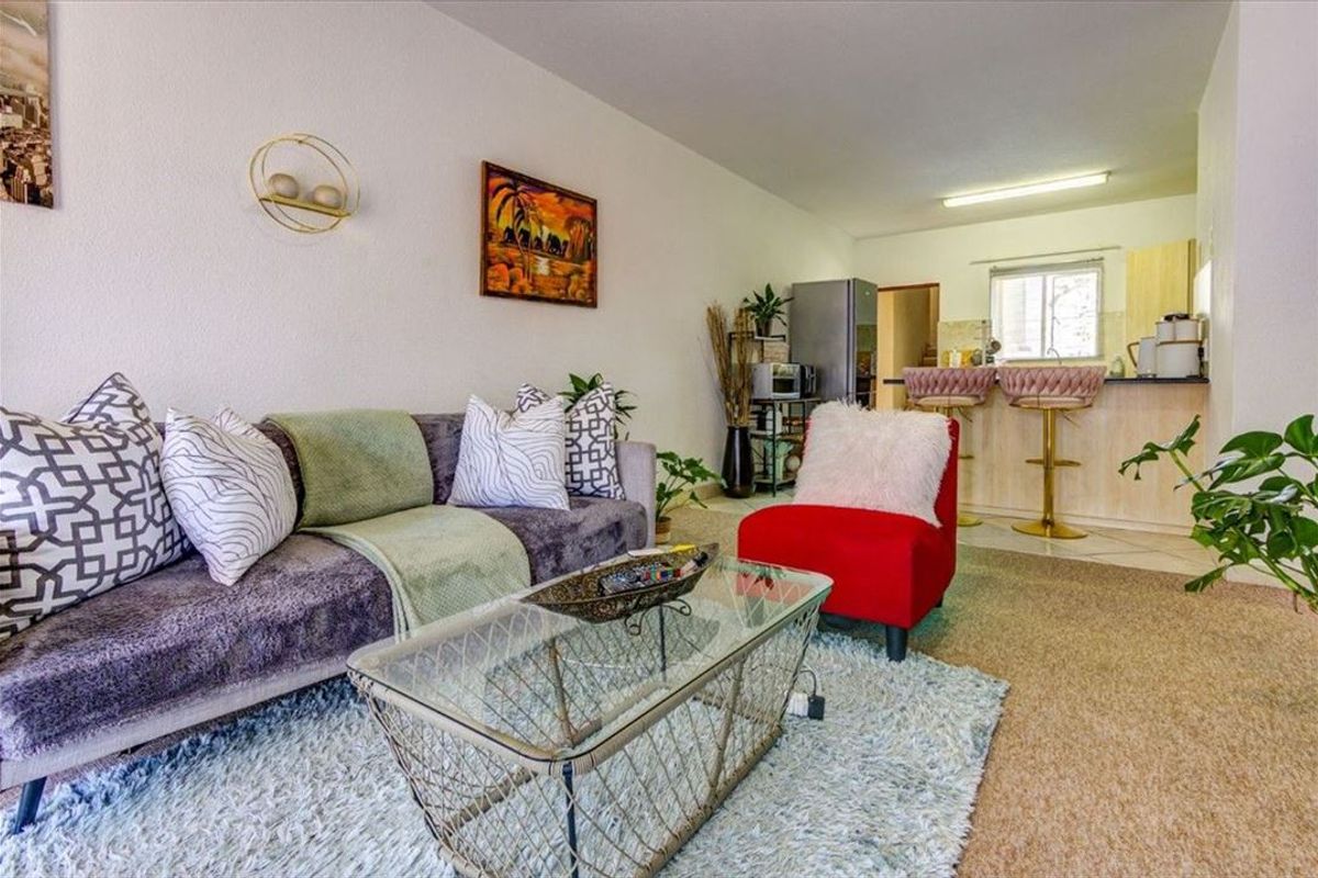 An open-plan living area featuring a combined lounge space and a functional kitchen with a breakfast bar and cabinetry.