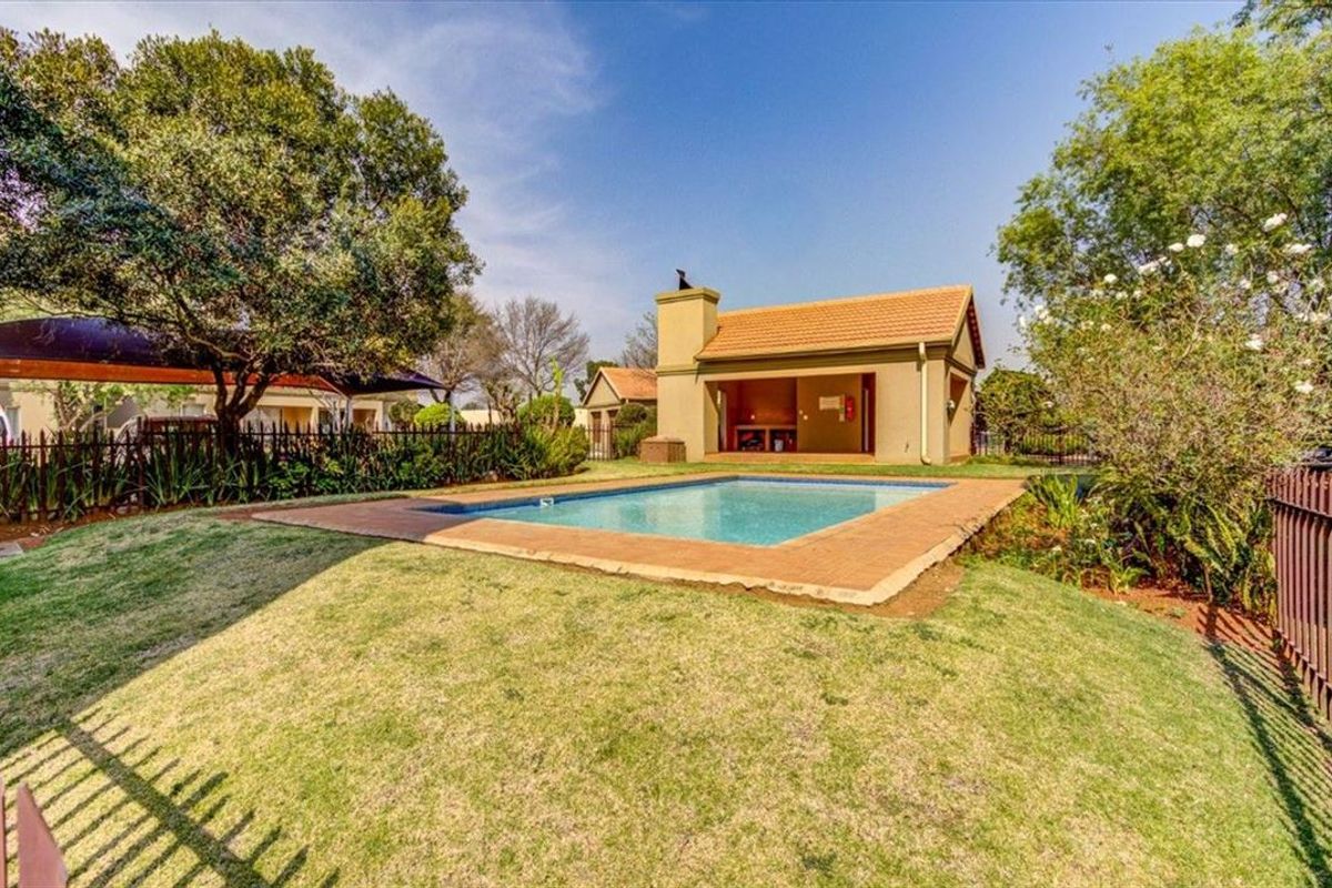 Outdoor pool area featuring a swimming pool with brick coping and a covered entertainment structure with a built-in braai.
