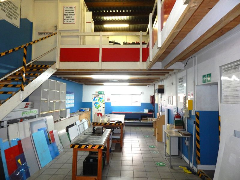 Industrial utility space featuring a mezzanine level, tiled flooring, exposed timber beams, and built-in storage shelving suitable for workshop or warehouse operations.