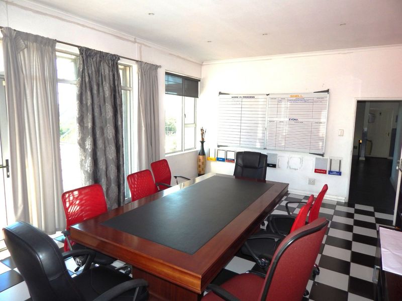 A functional office space featuring checkered floor tiles, large windows for natural light, and a wall-mounted whiteboard for collaborative work.