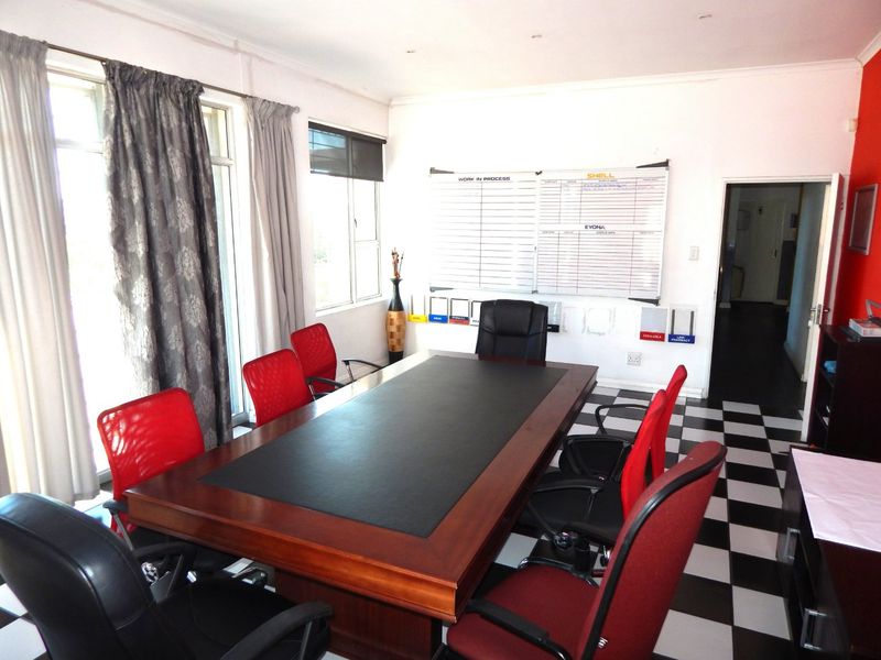 A functional office space featuring checkered floor tiles, recessed lighting, and a large sliding glass door providing natural light.