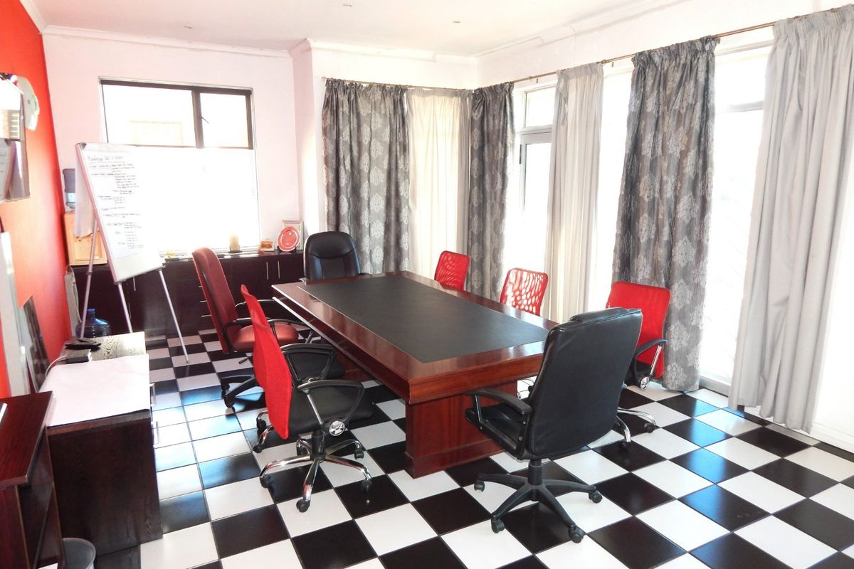 A functional office space featuring high-contrast checkered tile flooring, recessed lighting, and large windows providing ample natural light.