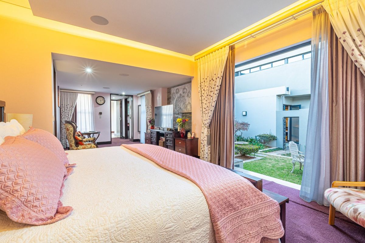 Spacious bedroom featuring recessed lighting, built-in ceiling speakers, and large sliding glass doors that open directly onto a private courtyard garden.