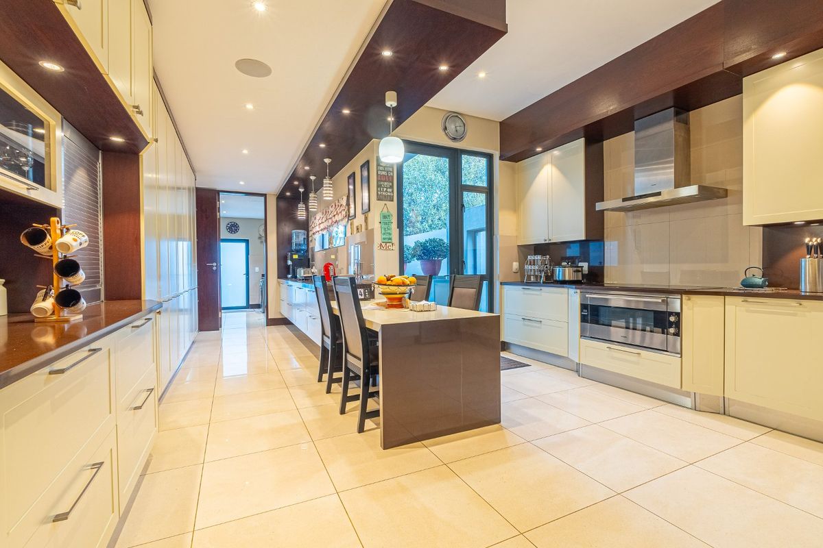 Modern kitchen featuring sleek built-in cabinetry, stone countertops, a central island, and high-quality stainless steel appliances with integrated lighting.