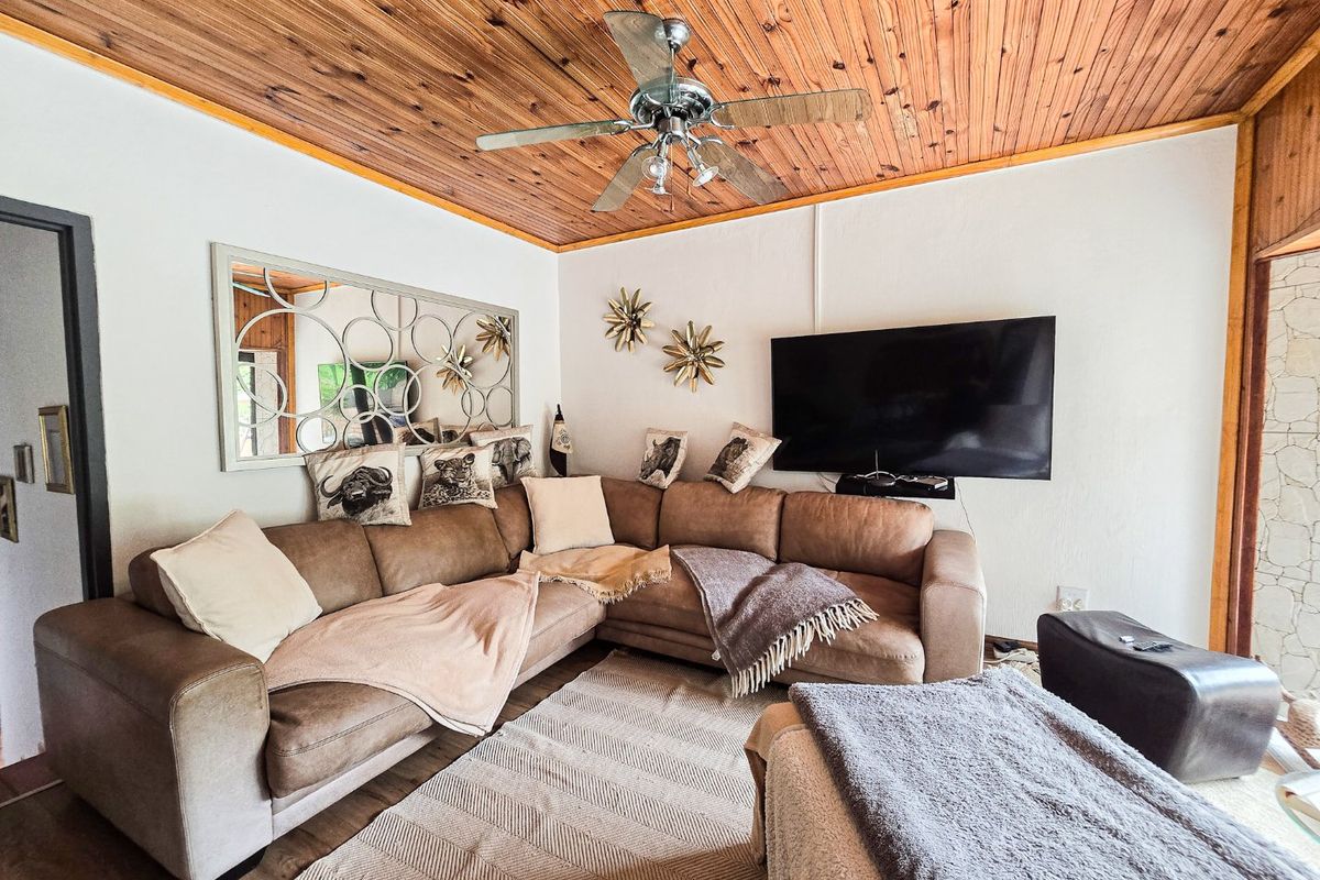 A cozy living room featuring a warm timber tongue and groove ceiling with an integrated ceiling fan.