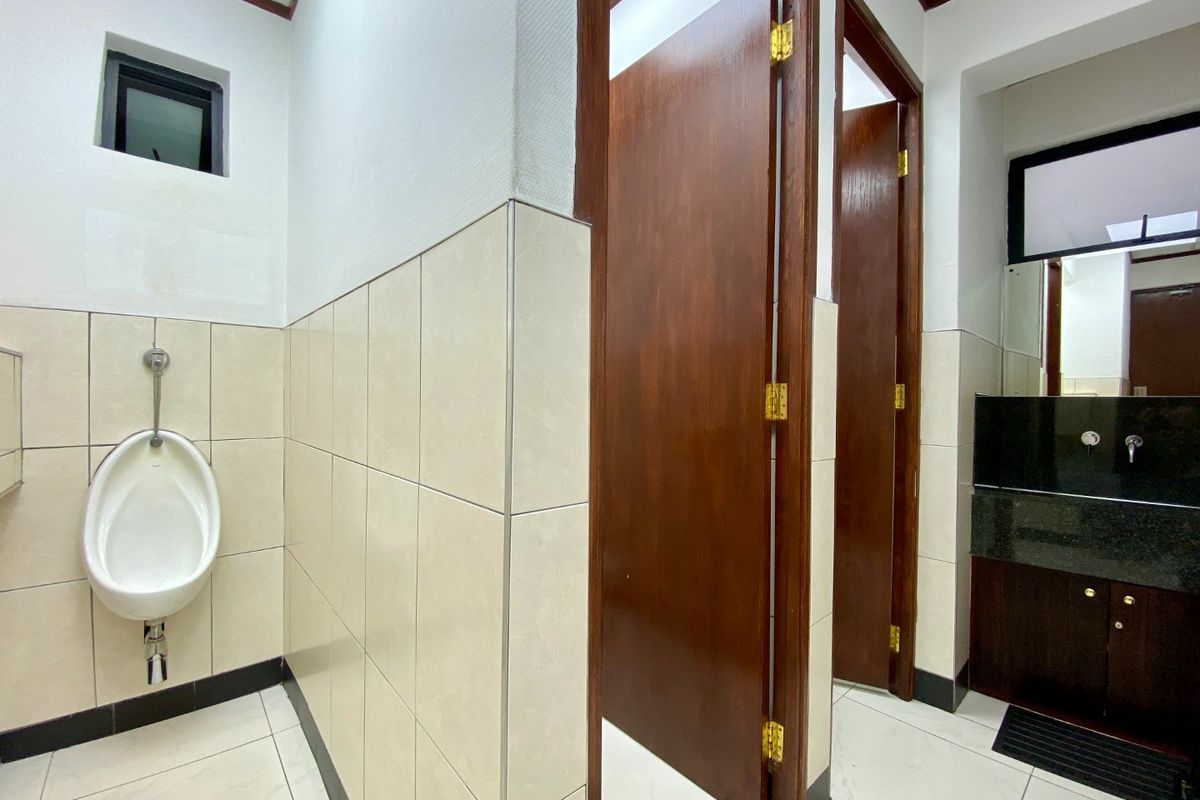 Commercial restroom facility featuring a wall-mounted urinal, tiled finishes, and a vanity area with a granite countertop.