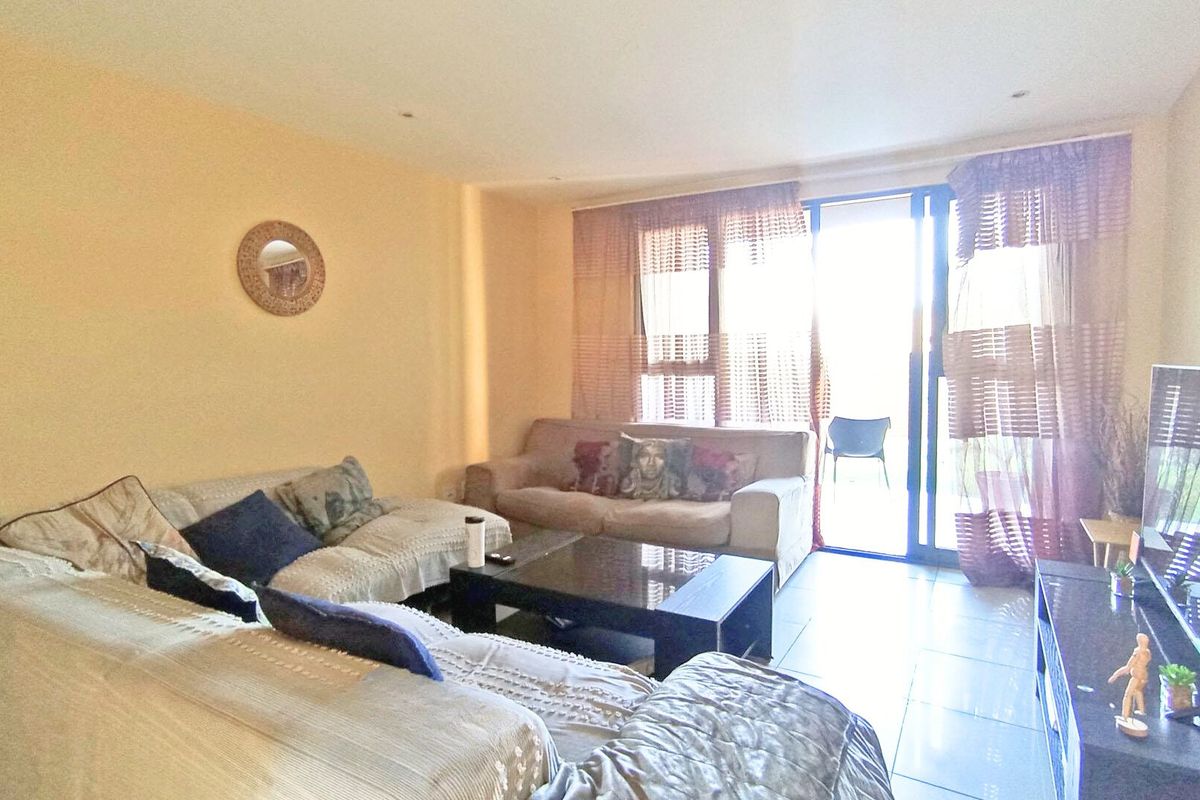 A living room featuring tiled flooring, recessed ceiling lights, and a sliding glass door providing access to an outdoor balcony area.