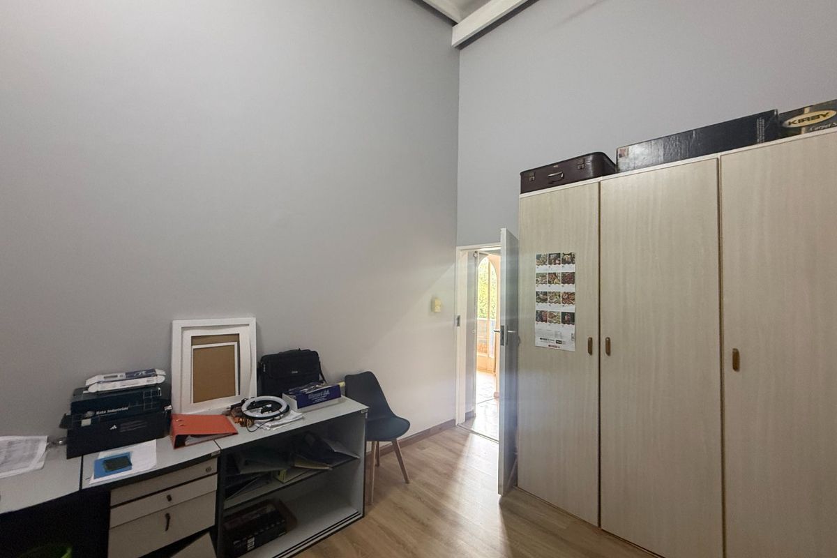 A bedroom featuring high ceilings, laminate flooring, and a built-in wardrobe, with direct access to an outdoor area.