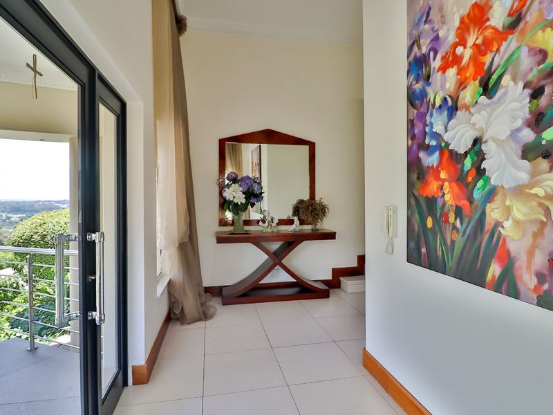 Bright entrance hall featuring tiled flooring, modern skirting boards, and a glass sliding door providing access to an outdoor balcony area.