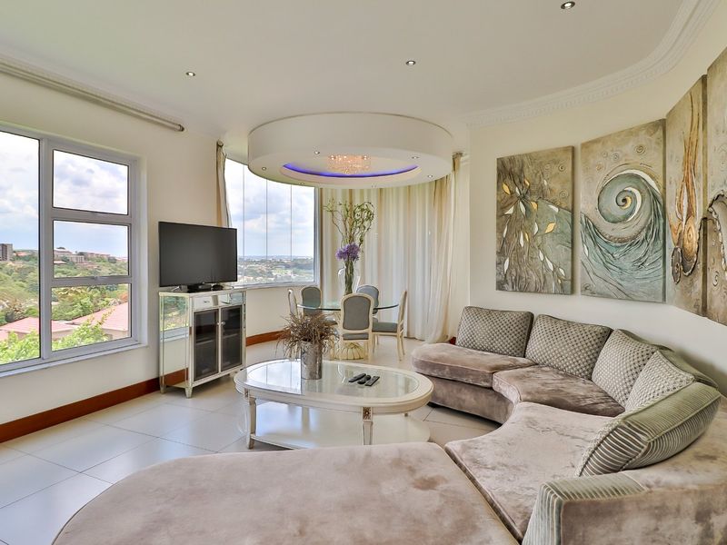 A bright and spacious living room featuring large windows with panoramic views, tiled flooring, and a distinctive circular recessed ceiling detail.