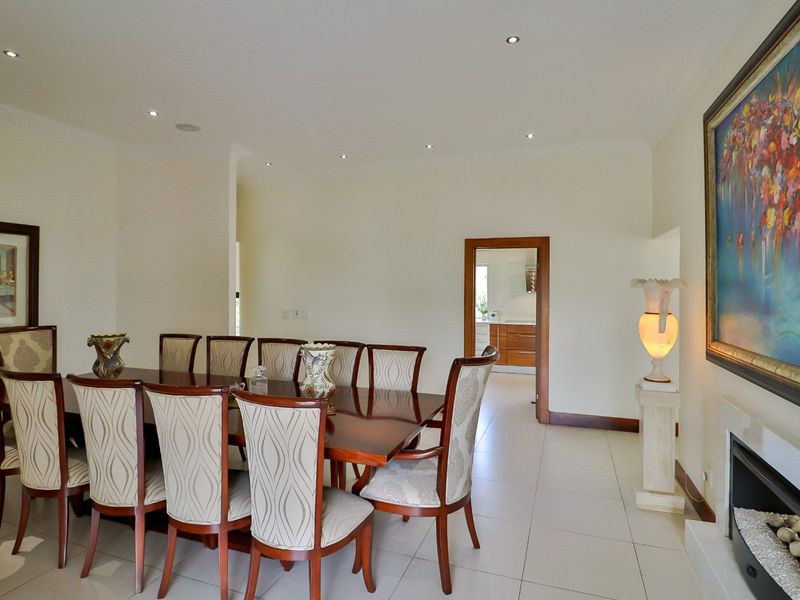 A spacious dining room featuring tiled flooring, recessed downlighting, and a built-in fireplace, with an open transition to the adjacent kitchen area.