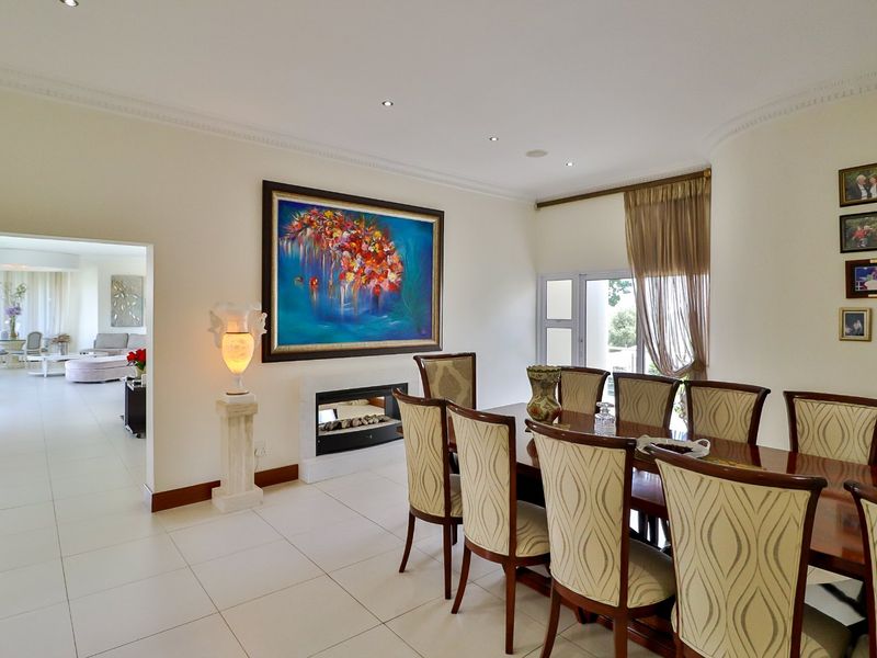 Spacious dining room featuring tiled flooring, recessed downlights, elegant cornicing, and a modern built-in fireplace, with seamless flow to the adjacent living area.
