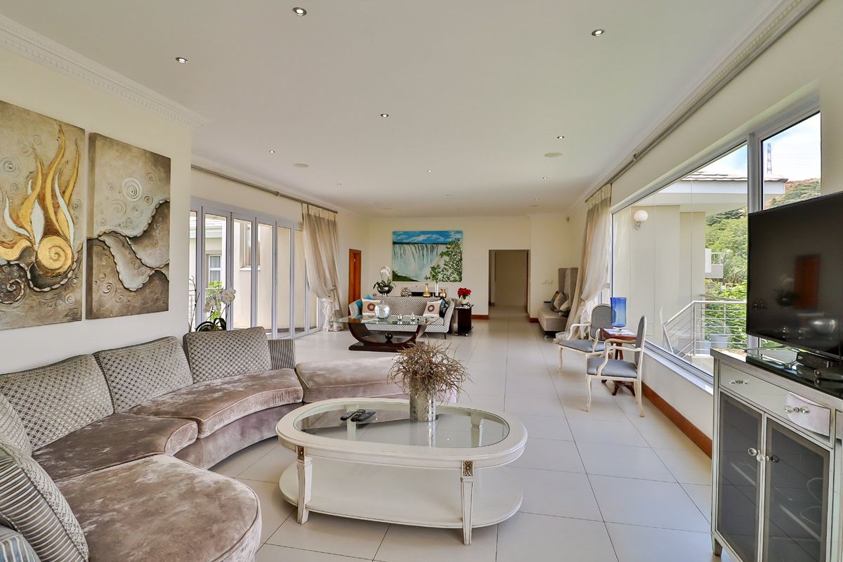 Spacious, light-filled living room featuring large sliding glass doors, neutral tiled flooring, and recessed downlighting, offering a seamless transition to outdoor areas.