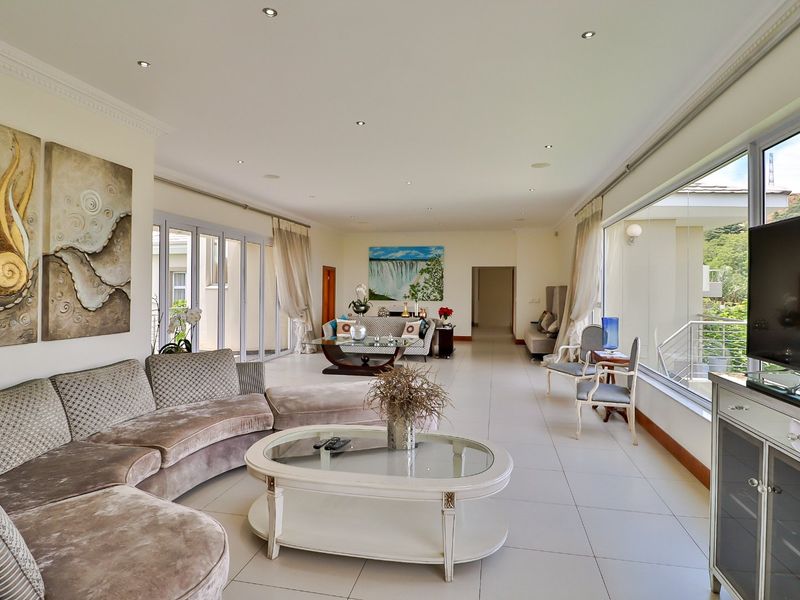 Spacious, light-filled living room featuring large sliding glass doors, neutral tiled flooring, and recessed downlighting, offering a seamless transition to outdoor areas.
