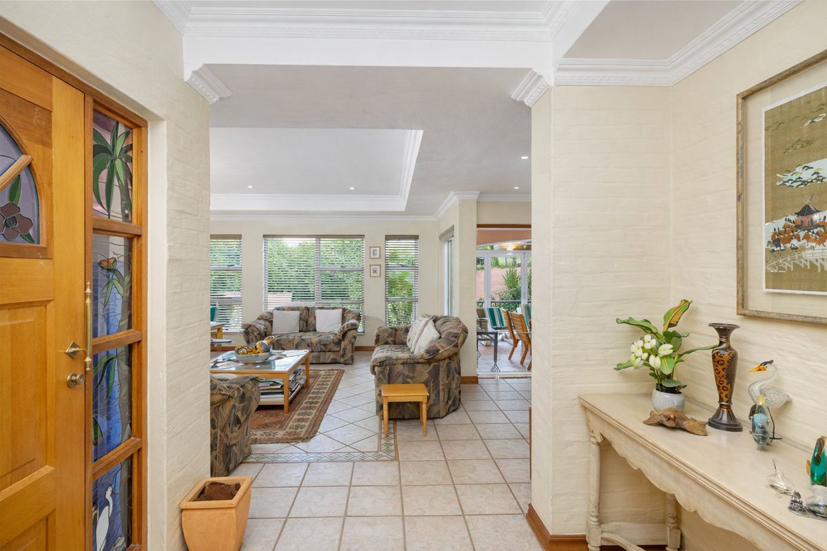 Entrance foyer leading into a spacious living area with ceramic tiled flooring, recessed ceiling details, and a feature stained glass timber front door.