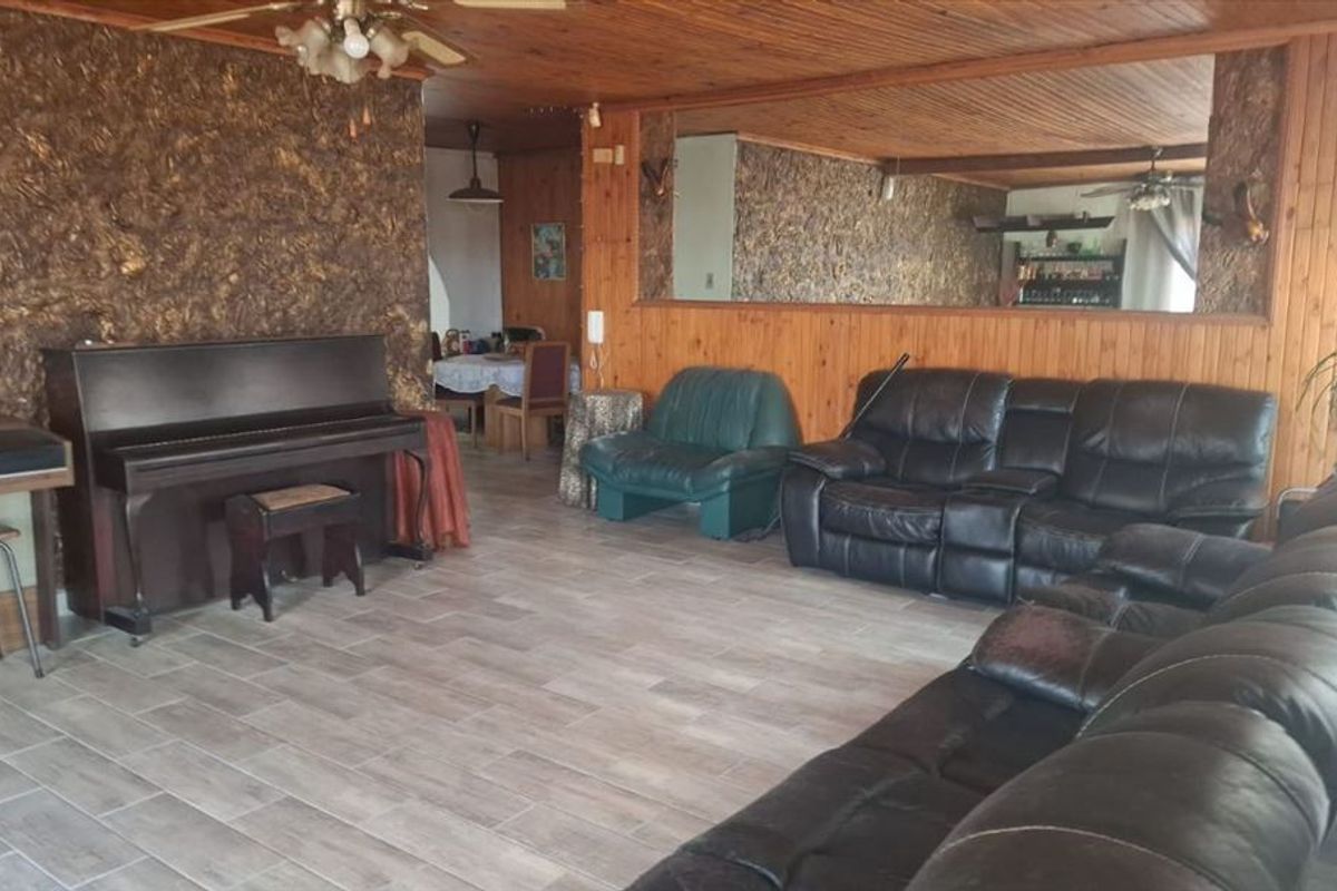 Spacious living area featuring timber wall paneling, a textured feature wall, large wall mirror, and tiled flooring throughout.