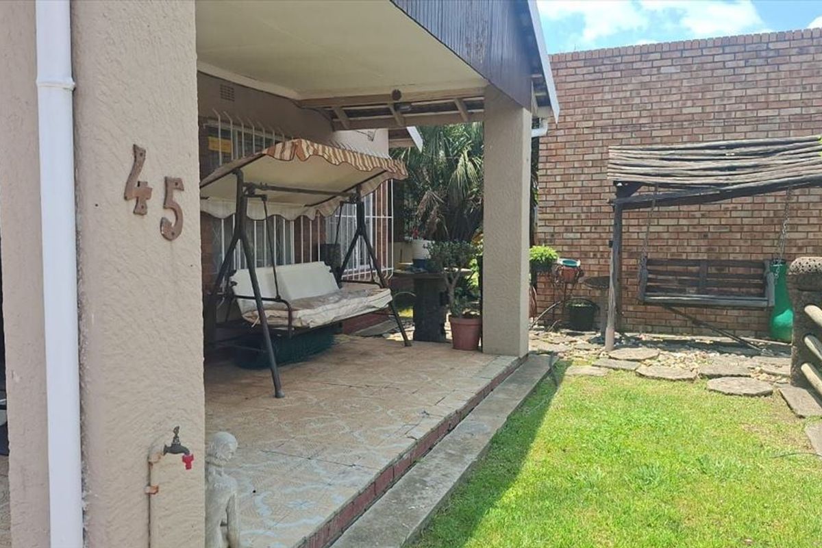 Covered patio area featuring tiled flooring and direct access to the garden, providing a functional outdoor space for relaxation.