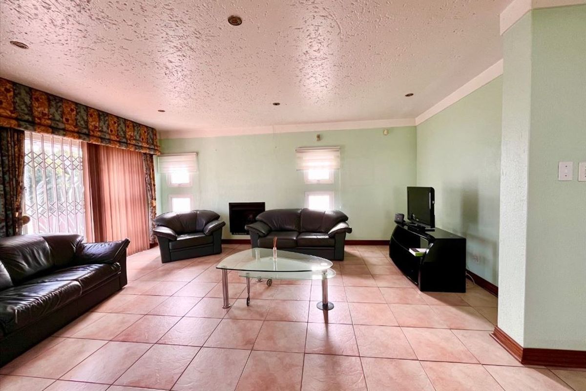 Spacious living room featuring tiled flooring, a built-in fireplace, and recessed lighting, offering a comfortable area for relaxation and family gatherings.