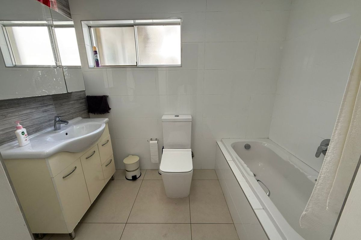 A functional bathroom featuring a vanity with basin, a toilet, and a bathtub with tiled finishes throughout.