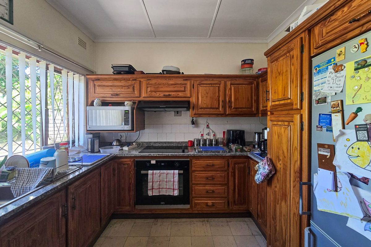 A functional kitchen featuring traditional wooden cabinetry, granite countertops, built-in oven, and hob, offering a classic layout with ample storage space.