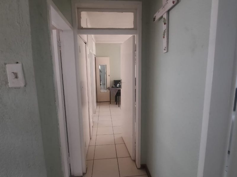 A narrow hallway featuring tiled flooring and built-in storage, connecting multiple rooms within the townhouse.