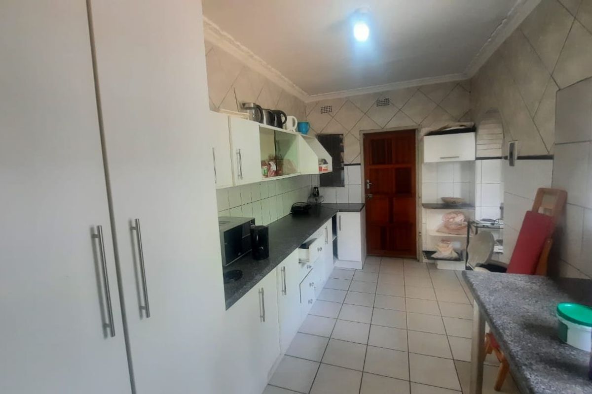 A functional kitchen featuring built-in cabinetry, laminate countertops, and tiled flooring, offering a practical layout with potential for modern updates.