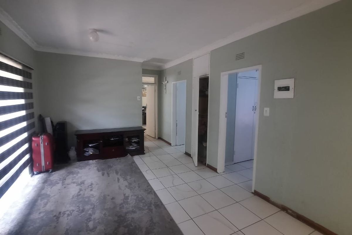 A living area featuring tiled flooring, built-in storage cupboards, and modern zebra blinds, providing a functional space with neutral wall tones.