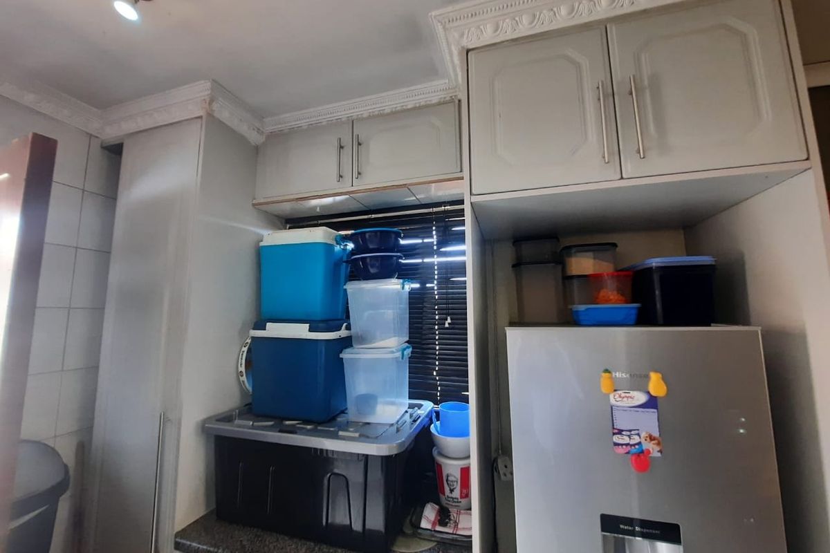 A functional kitchen area featuring built-in cabinetry, granite countertops, and decorative ceiling cornices, providing practical storage and workspace.