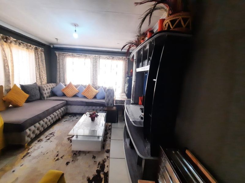 A comfortable living room featuring tiled flooring and large windows that allow for natural light, providing a functional and inviting space.