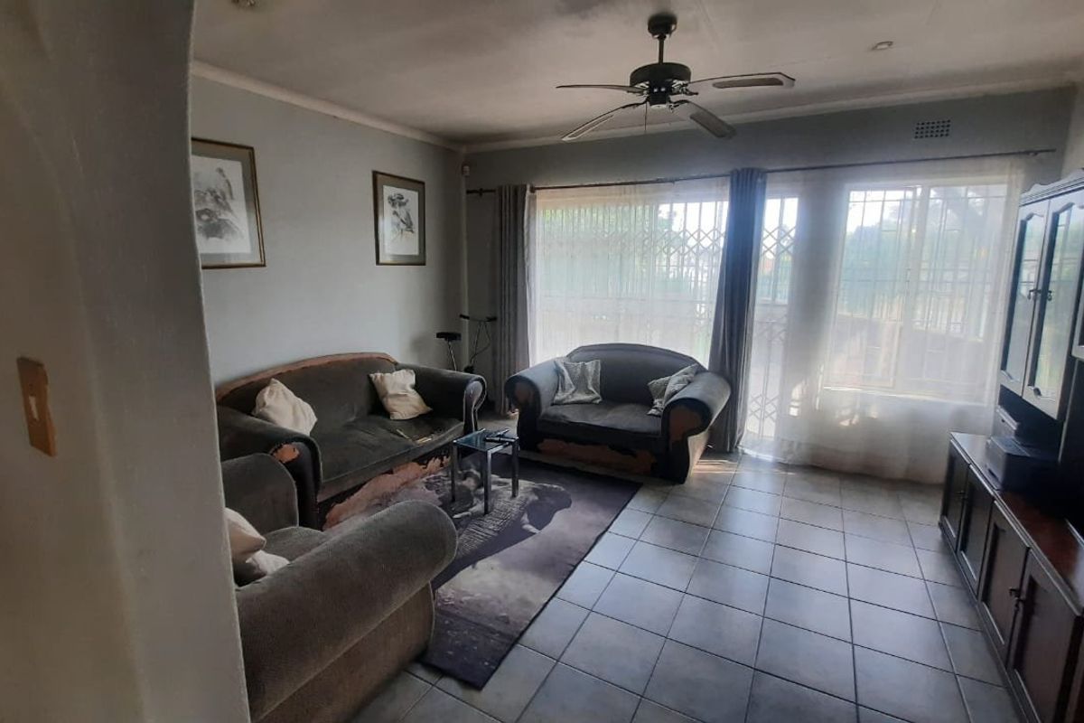 A living room featuring tiled flooring, a ceiling fan, and a sliding door with security gate access to the exterior.