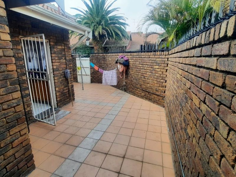 A private rear courtyard featuring face brick boundary walls with security spikes and paved patio flooring.